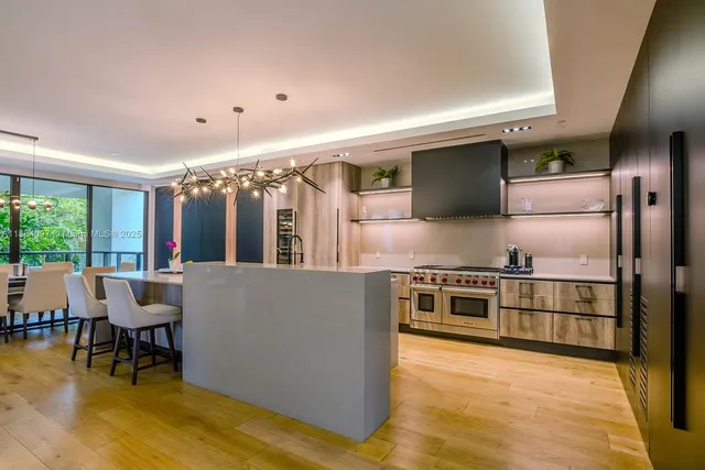 a kitchen with stainless steel appliances kitchen island granite countertop a refrigerator a stove a sink and a dining table with garden view