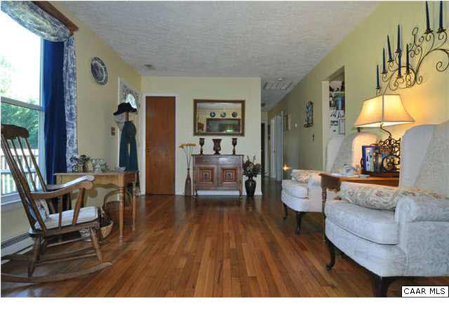Another view of the living room, showing front door on the left and hallway to bedrooms on the right.