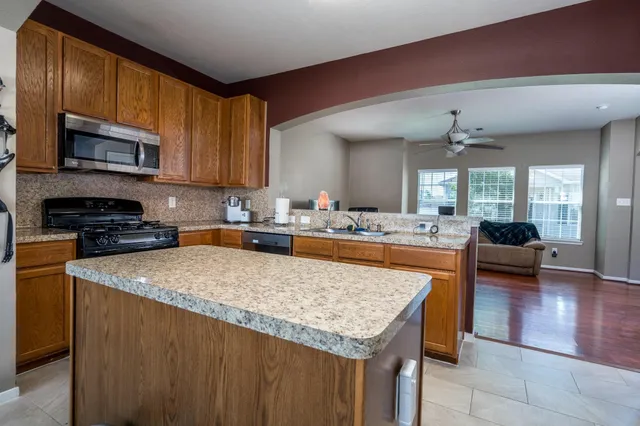 a kitchen with stainless steel appliances granite countertop a stove top oven a sink dishwasher and white cabinets with wooden floor