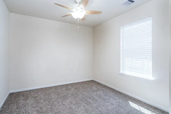 an empty room with a window and a fan