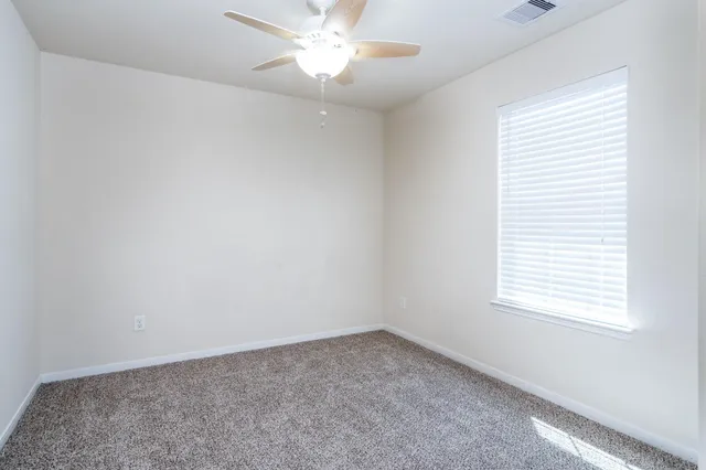 an empty room with a window and a fan