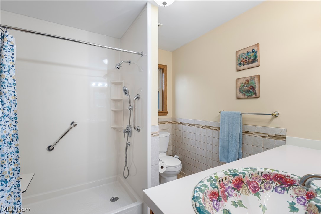 10909 Ruby Road Cambridge, OH 43725 - Photo 21 of 34 Bathroom with tile walls, vanity, a stall shower, and a wainscoted wall