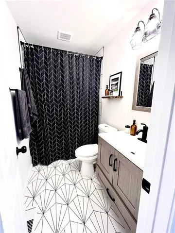 a bathroom with a sink a toilet a mirror and shower