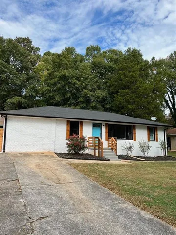 a front view of house with yard and trees in the background