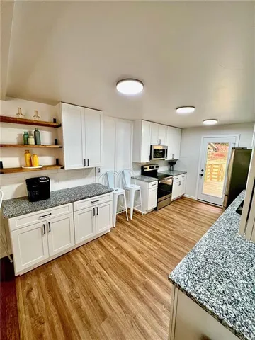a kitchen with stainless steel appliances granite countertop a sink dishwasher stove top oven and refrigerator with wooden floor