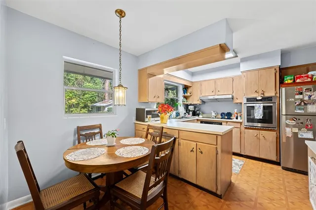 a kitchen with stainless steel appliances granite countertop a sink a stove a dining table and chairs
