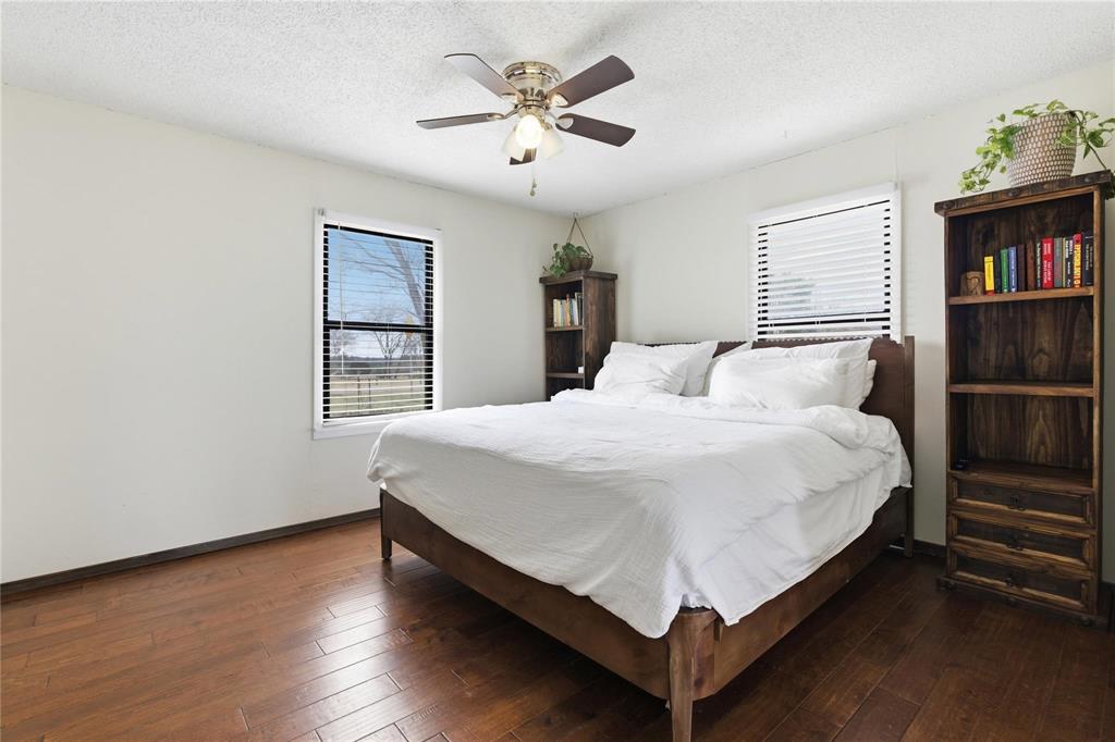 9213 Wilson Road Pilot Point, TX 76258 - Photo 14 of 36 Bedroom featuring wood-finish flooring, two windows with horizontal blinds, and a ceiling fan with integrated lighting