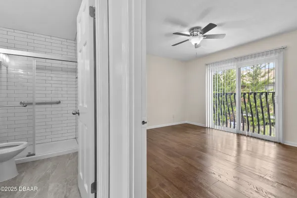 an empty room with wooden floor and a ceiling fan
