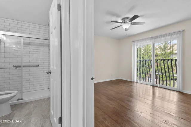 an empty room with wooden floor and a ceiling fan