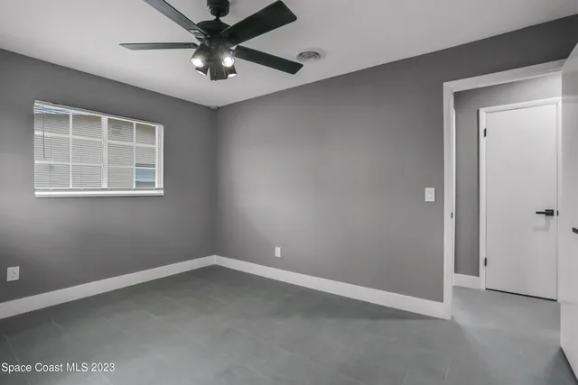 an empty room with a window and a fan