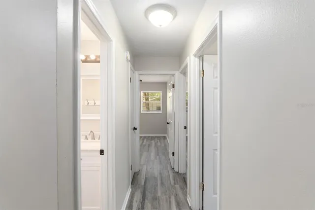 a view of a hallway with wooden floor and a bathroom