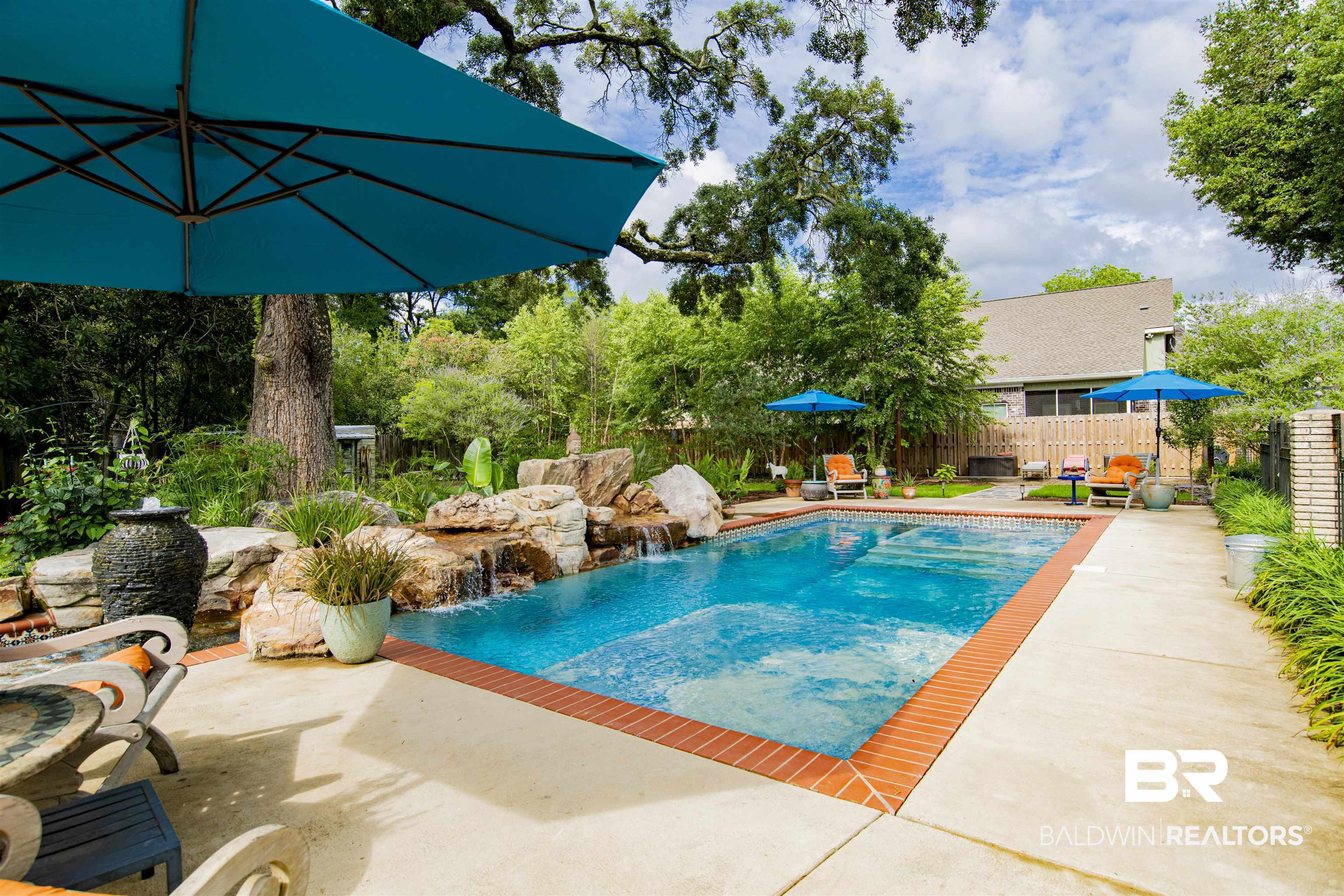 809 Bernard Circle Mobile, AL 36693 - Photo 3 of 75 Outdoor swimming pool with brick coping, an integrated rock waterfall feature, and a surrounding concrete patio
