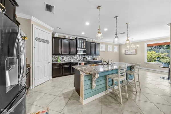 a kitchen with stainless steel appliances kitchen island granite countertop a stove top oven a refrigerator a kitchen island a table and chairs