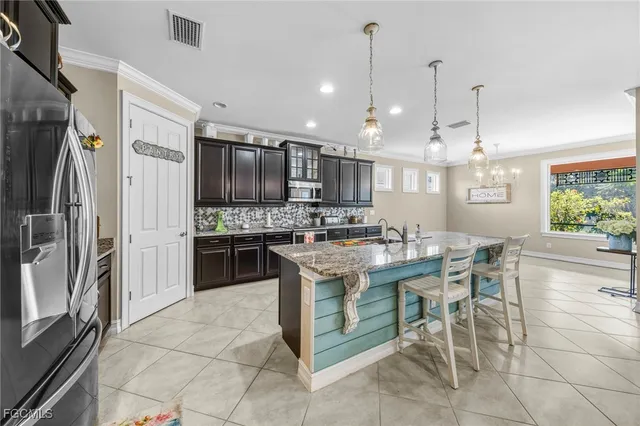 a kitchen with stainless steel appliances kitchen island granite countertop a stove top oven a refrigerator a kitchen island a table and chairs