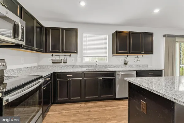 a kitchen with stainless steel appliances granite countertop a stove microwave and sink