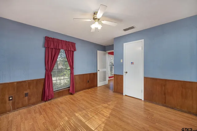 an empty room with wooden floor fan and windows