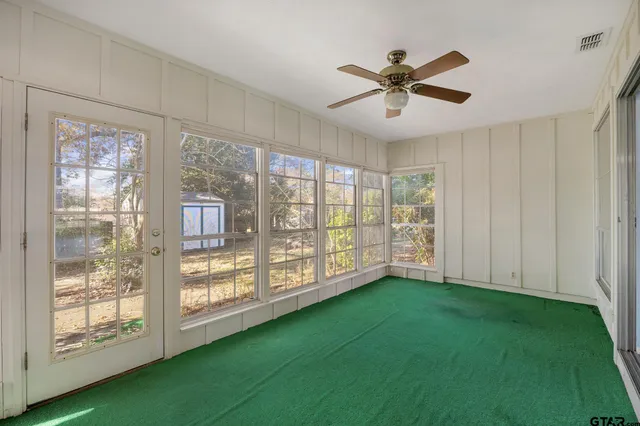 a view of empty room with floor to ceiling window and ceiling fan