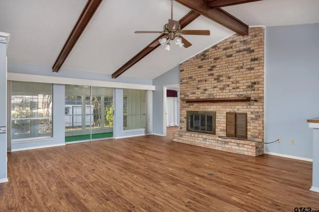 a view of an empty room with wooden floor and a fireplace