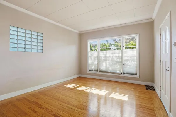 a view of empty room with wooden floor and fan