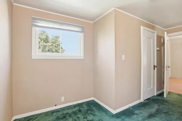 a view of an empty room with closet and a window