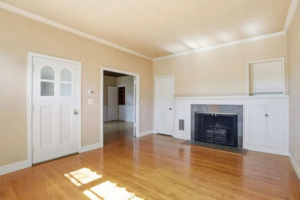 an empty room with wooden floor fireplace and windows