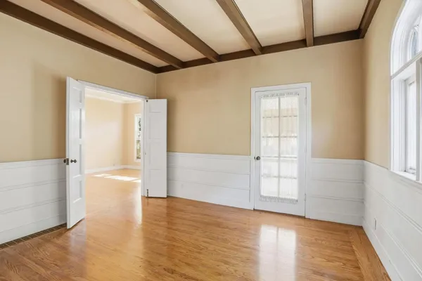 a view of an empty room with window and wooden floor