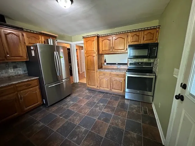 a kitchen with granite countertop a refrigerator and a stove top oven