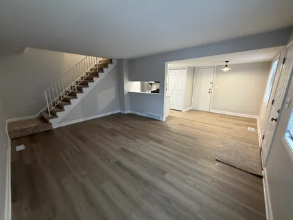 a view of a hallway with wooden floor and stairs