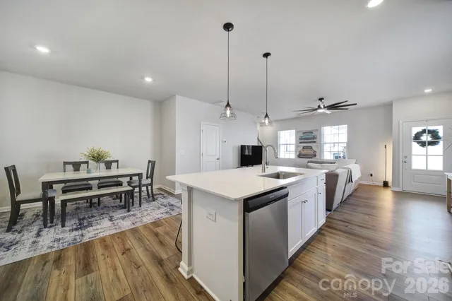 a large kitchen with kitchen island a island a stove a sink a dining table and chairs with wooden floor