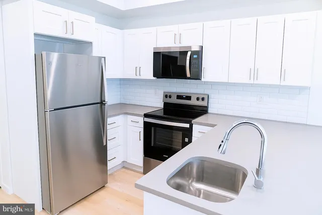 a kitchen with stainless steel appliances a refrigerator a stove a microwave a sink and cabinets