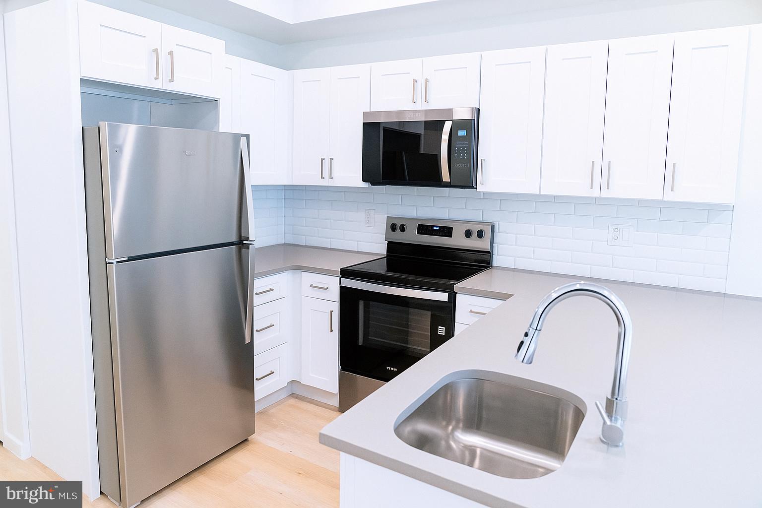 a kitchen with stainless steel appliances a refrigerator a stove a microwave a sink and cabinets