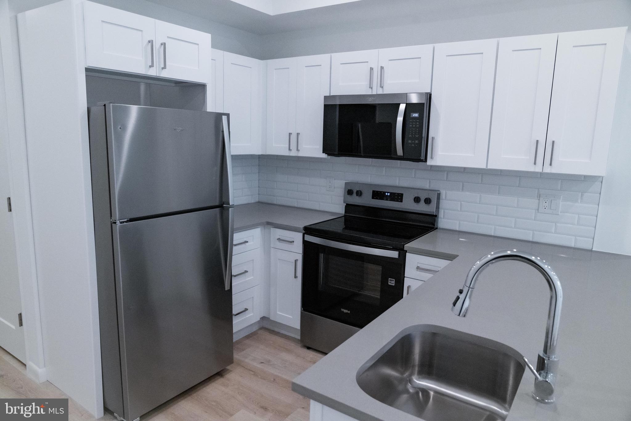 7248 Rising Sun Avenue, Unit 201 Philadelphia, PA 19111 - Photo 7 of 20 a kitchen with stainless steel appliances a refrigerator a stove a microwave a sink a refrigerator and cabinets