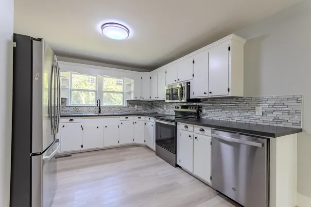 a kitchen with granite countertop white cabinets and white appliances