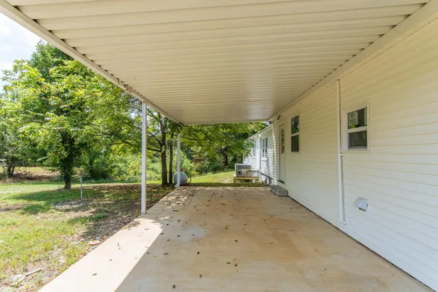 a view of yellow house with a big yard potted plants and large tree