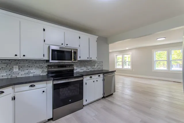a kitchen with granite countertop white cabinets and white appliances