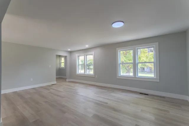 a view of an empty room with a window and wooden floor