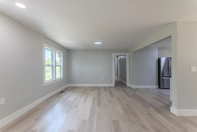 an empty room with wooden floor and windows