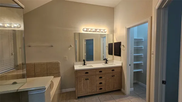 a bathroom with a double vanity sink mirror and bathtub