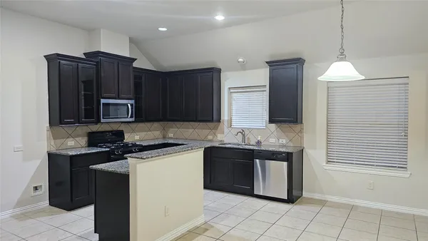 a kitchen with stainless steel appliances granite countertop a stove a sink and a microwave