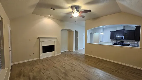 a view of a livingroom with a fireplace a ceiling fan and wooden floor