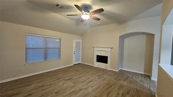 a view of an empty room with a fireplace and a window