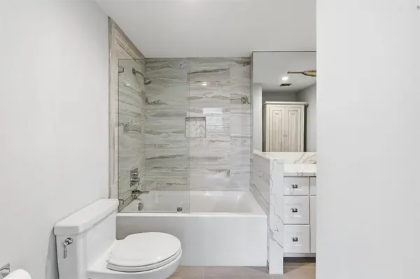 a bathroom with a bathtub shower sink vanity and toilet