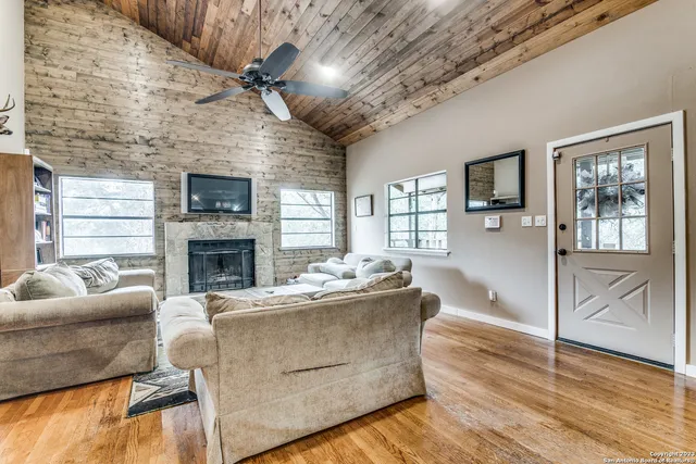 a living room with furniture a fireplace a flat screen tv and a large window
