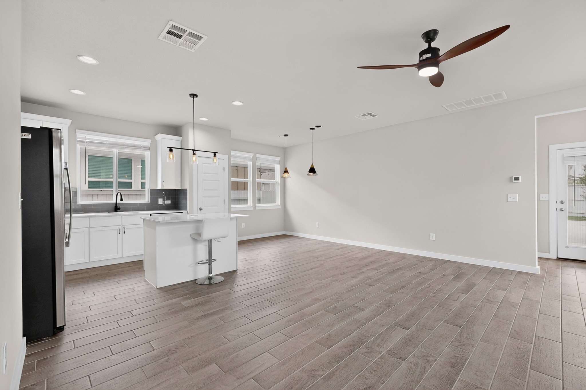 116 Appleberry Lane Elgin, TX 78621 - Photo 7 of 35 A contemporary open-concept space features a sleek kitchen island, ample natural light, and elegant wood-look tile flooring.