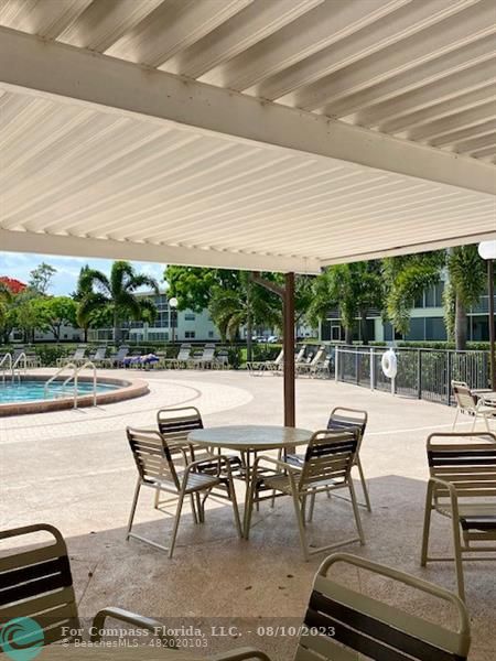 211 Mansfield East, Unit 211 Boca Raton, FL 33434 - Photo 14 of 14 a view of a patio with a dining table and chairs with wooden floor
