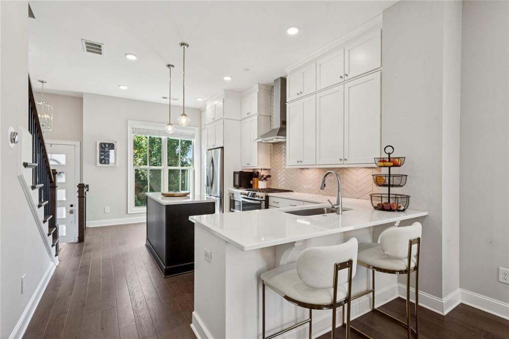 4219 Deming Circle Sandy Springs, GA 30342 - Photo 14 of 43 a kitchen with stainless steel appliances granite countertop a stove a sink a refrigerator and a dining table with wooden floor