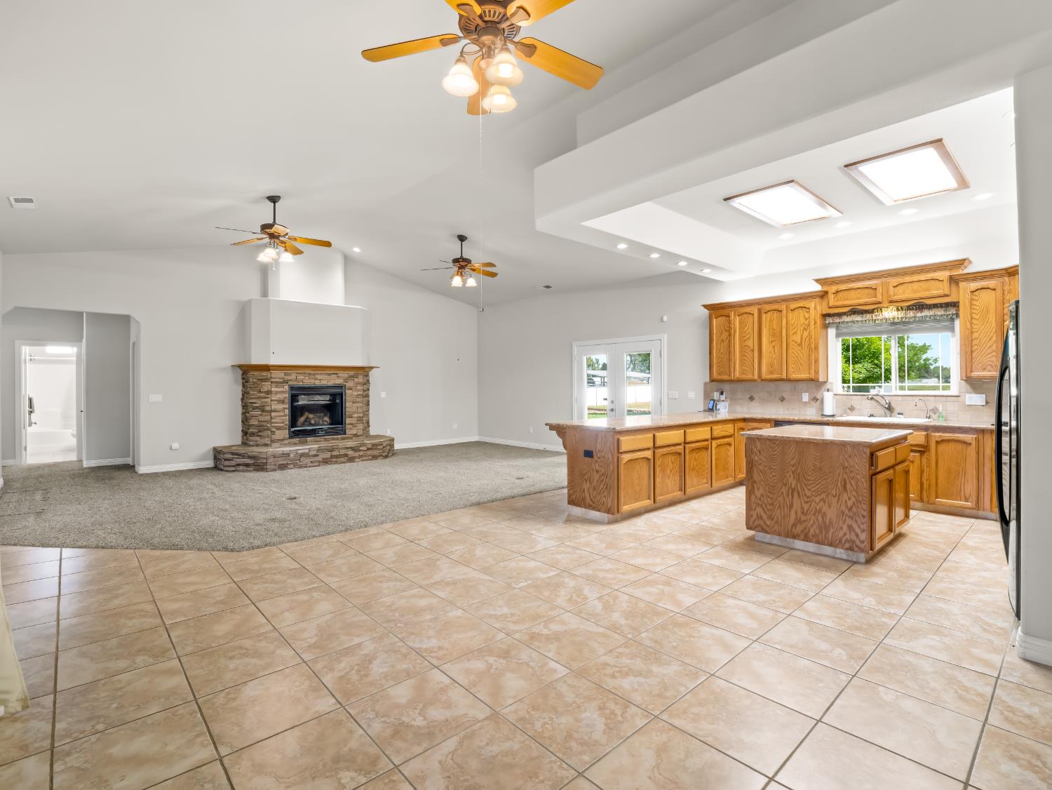 16389 Monreal Road Madera, CA 93636 - Photo 16 of 52 a large kitchen with a stove a sink dishwasher and a fireplace with wooden floor