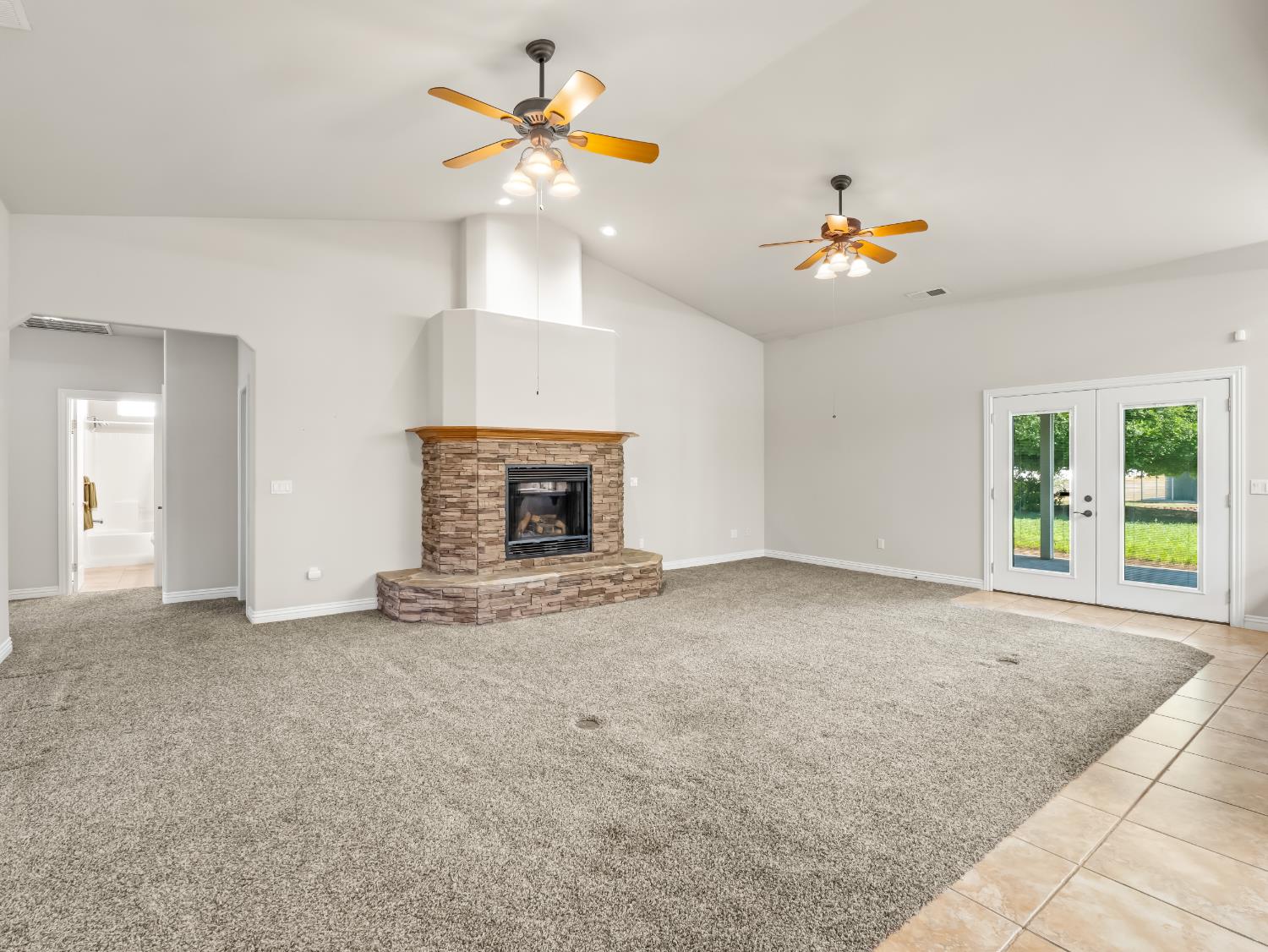 16389 Monreal Road Madera, CA 93636 - Photo 7 of 52 an empty room with a fireplace and windows