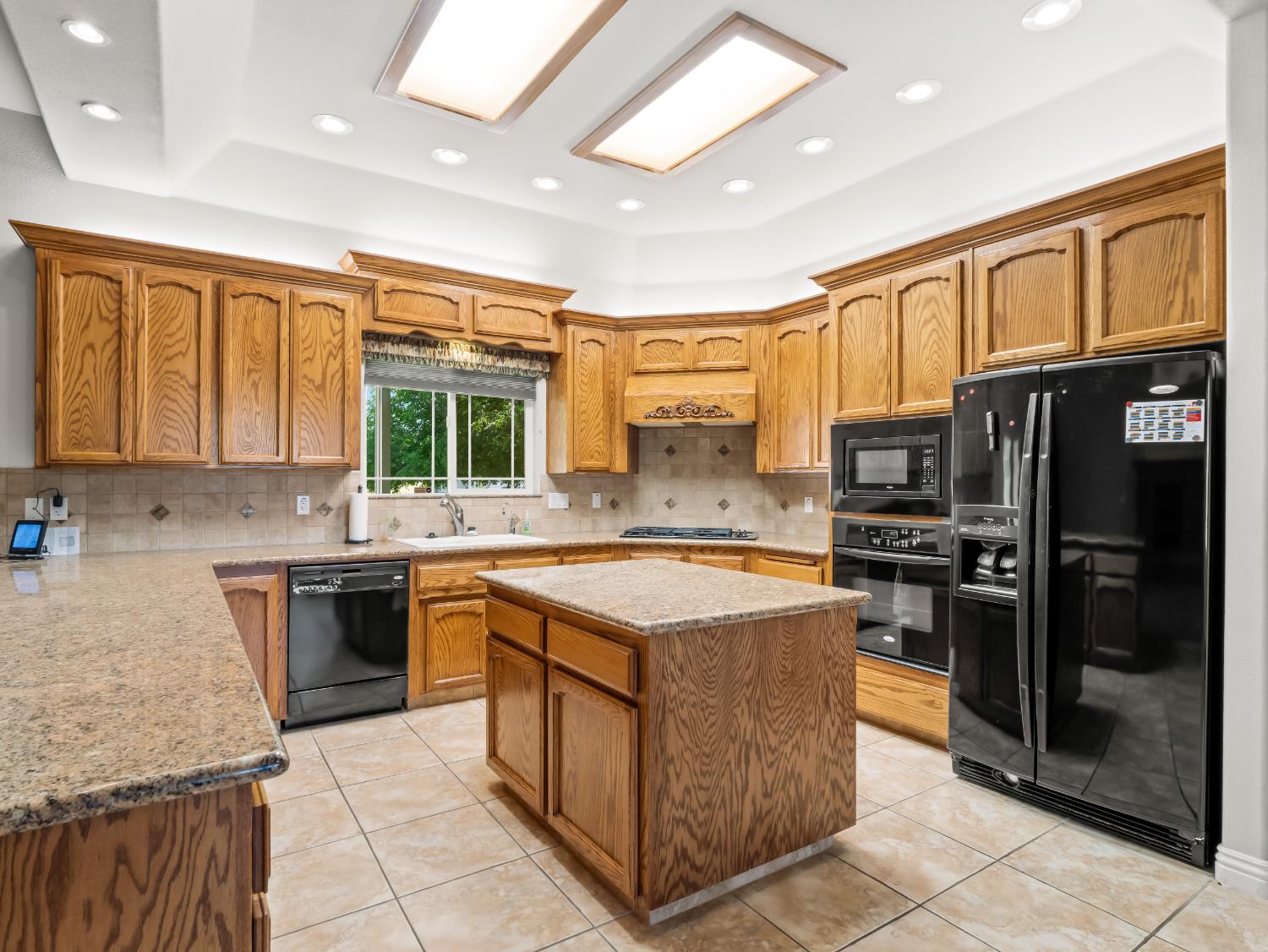 16389 Monreal Road Madera, CA 93636 - Photo 10 of 52 a kitchen with stainless steel appliances granite countertop a stove top oven a sink dishwasher and a refrigerator