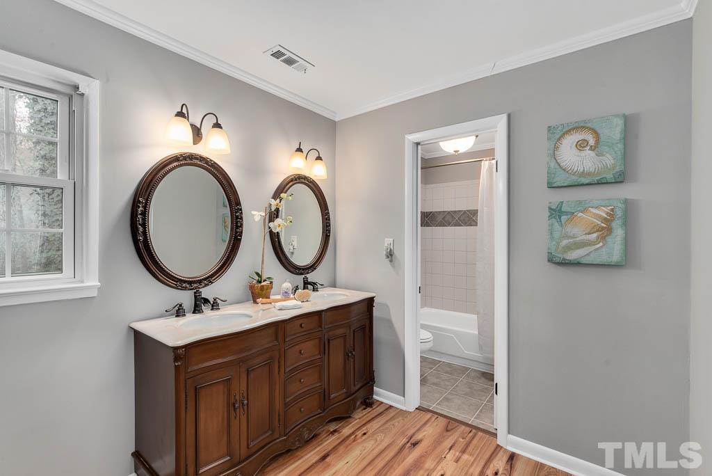 7405 Fiesta Way Raleigh, NC 27615 - Photo 22 of 38 a bathroom with a toilet a sink a mirror and a window